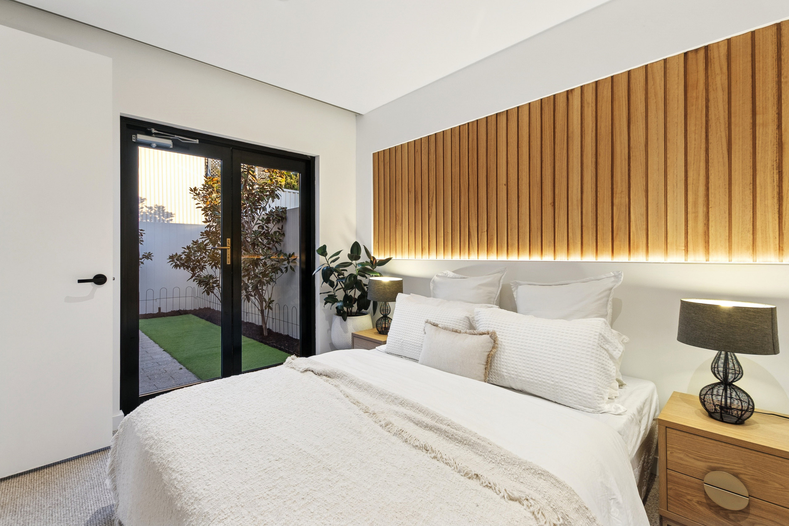 Bedroom in white linen opening to the garden through black French doors